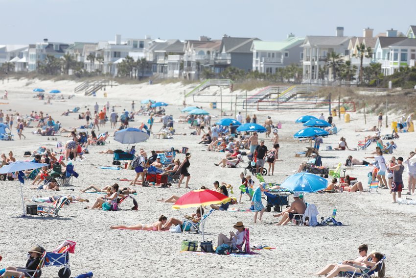Beach goers enjoy the Isle of Palms beach, Friday, March 20, 2020. City authorities are restricting access to the popular beach from 7 a.m. to 7 p.m. daily to help stop the spread of the coronavirus. (AP Photo/Mic Smith)