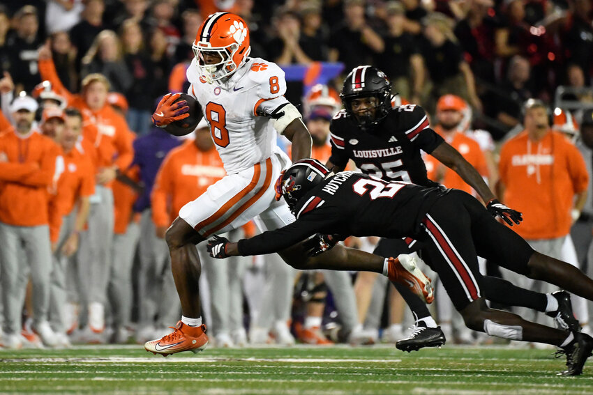 Clemson running back Adam Randall (8) attempts to avoid a diving tackle-attempt by Louisville defensive back D'Angelo Hutchinson in Louisville, Kentucky, on Friday, Nov. 14, 2025.