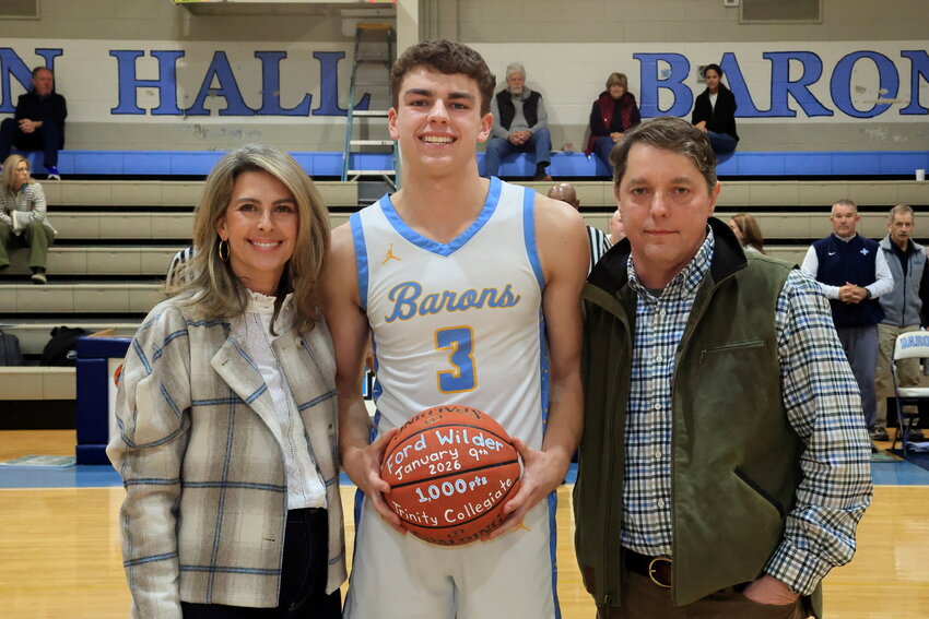Wilson Hall's Ford Wilder, center, is joined by his parents as he's celebrated for surpassing 1,000 points in his Baron basketball career on Tuesday.