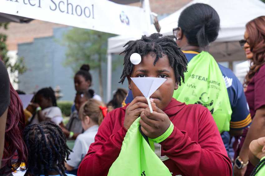 A student practices a scientific experiment involving the amount of air pressure needed to make a styrofoam ball levitate without leaving a funnel at the Liberty STEAM Charter School exhibit area on Saturday.