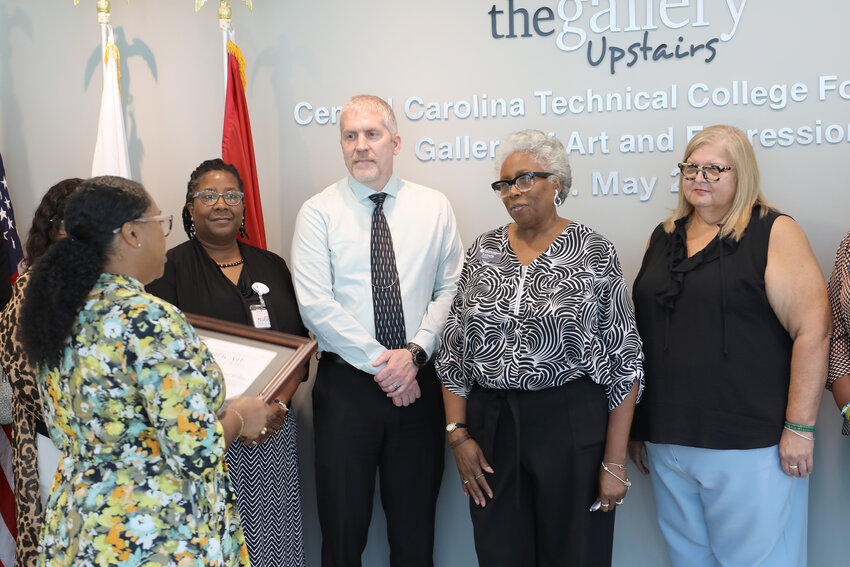 A representative of South Carolina's Department of Veterans Affairs presents a plaque to Central Carolina Technical College in recognition of its Veterans Upward Bound program receiving the Bronze Standard award.