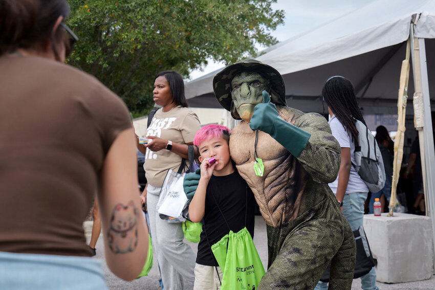 The Lizard Man, of Lee County folklore, was on hand during the eSTEAM Festival in downtown Sumter in early October and takes a picture with a child.