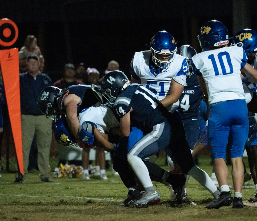 East Clarendon's Jesse Floyd (52) and Carsten Mellette (14) make a tackle against Lake City on Friday.